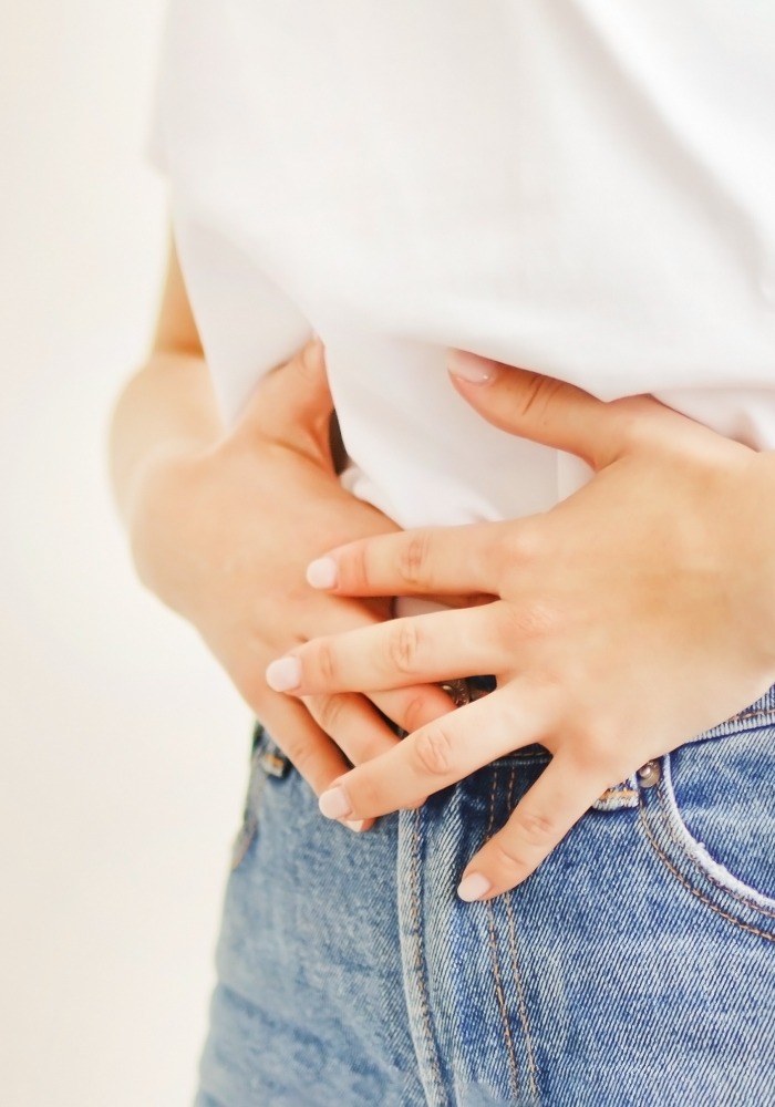 Woman suffering from stomach ache. Holding belly and feeling abdominal menstrual pain or bowel and digestion problems