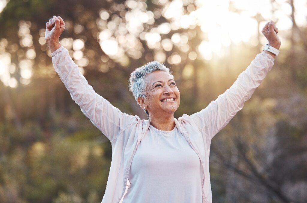 Eine ältere Frau, die im Freien lächelt und die Natur genießt – für Freiheit, Glück und einen gesunden Lebensstil mit Fitness und frischer Luft. Das Gesicht einer glücklichen schwarzen Frau im Park, die im Sommer für Frieden, Gesundheit und Wohlbefinden steht